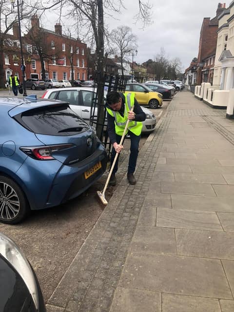 Litter picker sweeping beside parked cars in Old Town