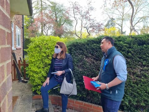 Jackson with blue rosette talking to a resident at a garden gate