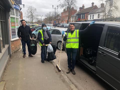 Jackson and volunteers with bags and a broom outside shops in Old Town