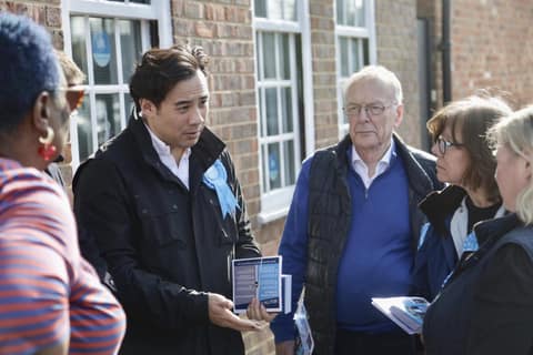 Jackson holding leaflets talking with residents outside houses
