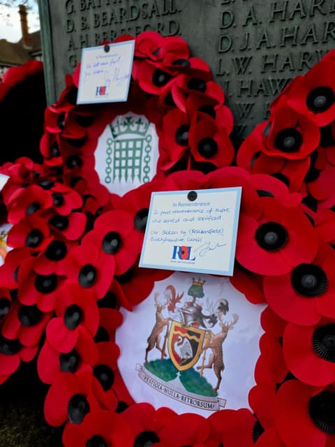 Close-up of poppy wreaths at the war memorial, including one with the Buckinghamshire Council crest